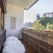 Balkon mit Sitzbank und Gartenblick.