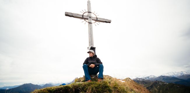 /media/gridteaser/kitzbueheler-alpen-hero-wandern-nick-brandstaetter-sitzt-am-gipfel-und-geniesst-die-aussicht-ueber-das-brixental-c-daniel-gollner-3.webp